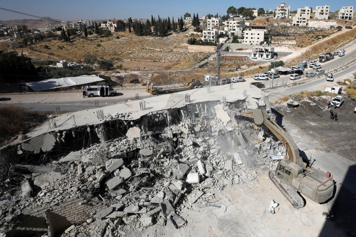 An Israeli military bulldozer demolishes a building near a military barrier in Sur Baher, a Palestinian village on the edge of East Jerusalem in an area that Israel captured and occupied in the 1967 M