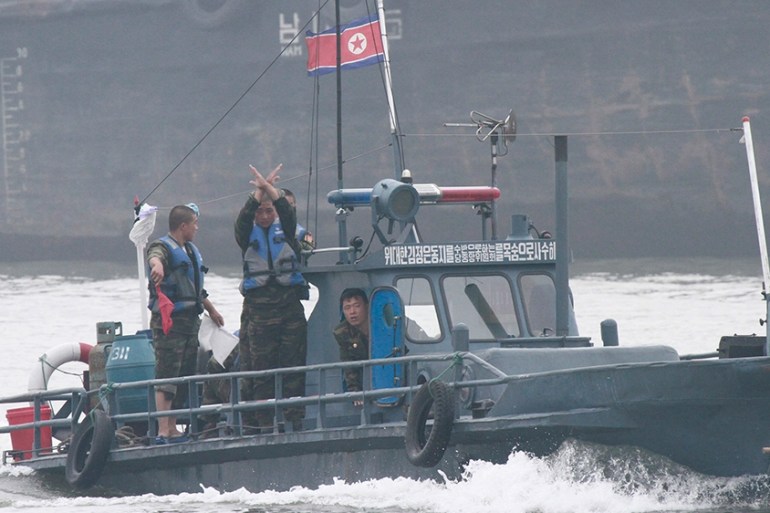 North Korean policemen gesture as they ask a North Korean fish boat to stop for inspection on the Yalu River near the North Korean town of Sinuiju, opposite the Chinese border city of Dandong, July 7,