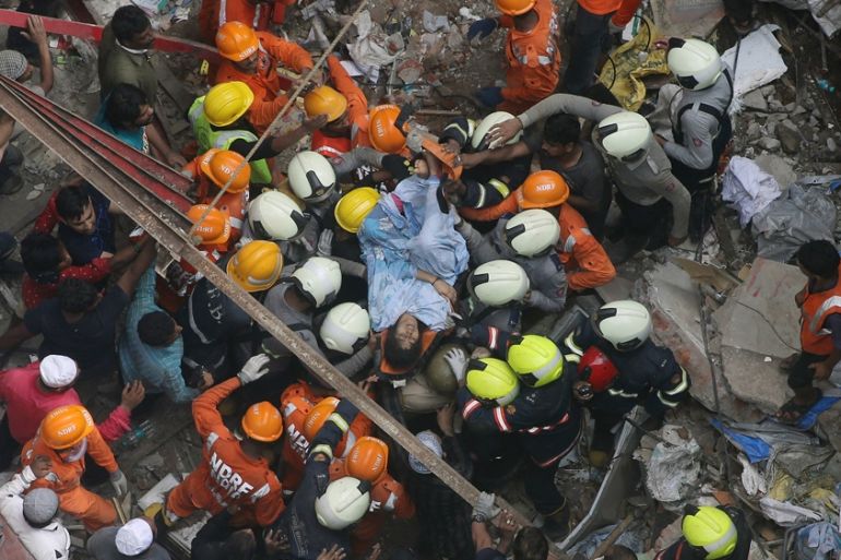 Rescuers carry out a survivor from the site of a building that collapsed in Mumbai, India, Tuesday, July 16, 2019. A four-story residential building collapsed Tuesday