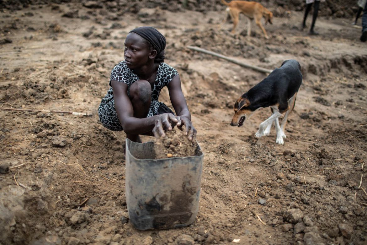 A woman uses her hands to collect loose dirt to remove from Mabil pond, on April 8, 2019. In return for completing the project, which is estimated to require 80 hours of labor over 20 days per worker,