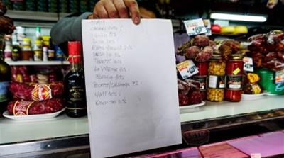 Luislist: Luis Coronel holds out a list of products offered at the cheese and charcuterie shop where he works whose prices from venders are slated to rise/Photo: Natalie Alcoba