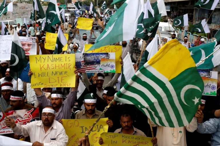 People hold flags and signs in solidarity with the people of Kashmir, during a rally in Karachi