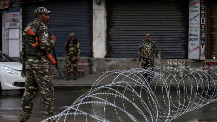 Indian security forces personnel stand guard next to concertina wire laid across a road during restrictions after the government scrapped special status for Kashmir, in Srinagar