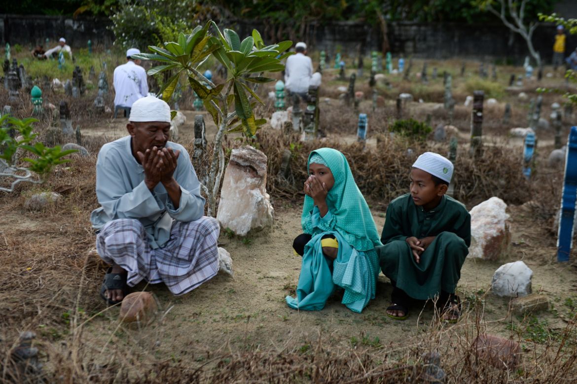 Thai Muslims pray before the tomb of their relatives at a cemetery during the Eid al-Adha festival in Thailand''s southern province of Narathiwat on August 11, 2019. - Muslims are celebrating Eid al-Ad