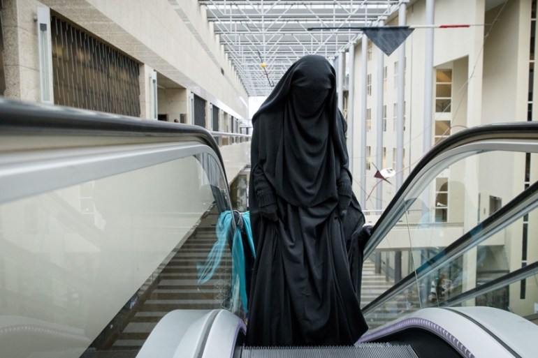 A visitor to the Second Chamber rides an escalator dressed in a niqab, prior to a debate on Islamic face covering in The Hague on November 23, 2016.