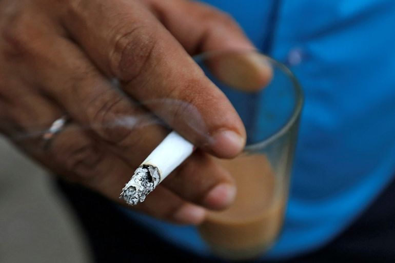 A man smokes a cigarette along a road in Mumbai, India