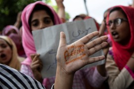 Kashmiri woman shows her hand with a message as others shout slogans during a protest in Srinagar