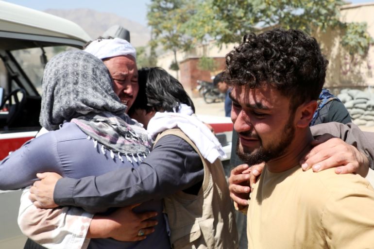 Afghan men comfort each other as they mourn during the funeral of their relatives after a suicide bomb blast at a wedding in Kabul