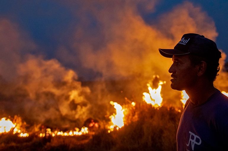 A labourer stares at a fire that spread to the farm he work on next to a highway in Nova Santa Helena municipality in northern Mato Grosso State, south in the Amazon basin in Brazil, on August 23, 201