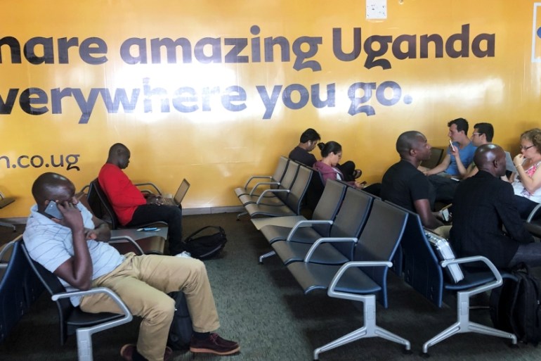 Passengers use their mobile phones at the departure lounge of the Entebbe international airport in Entebbe