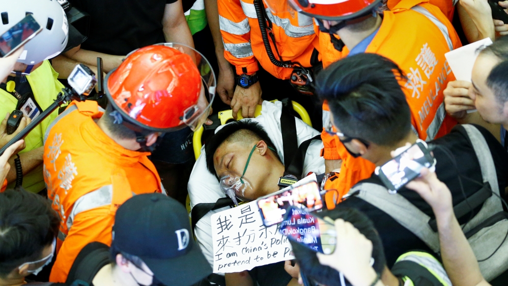 Medics attempt to remove an injured man, who some anti-government protesters said was an undercover police officer from mainland China, at the airport in Hong Kong