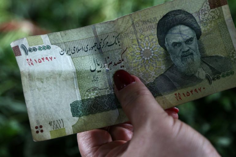 A woman holds an Iranian currency in Tajrish bazaar in Tehran