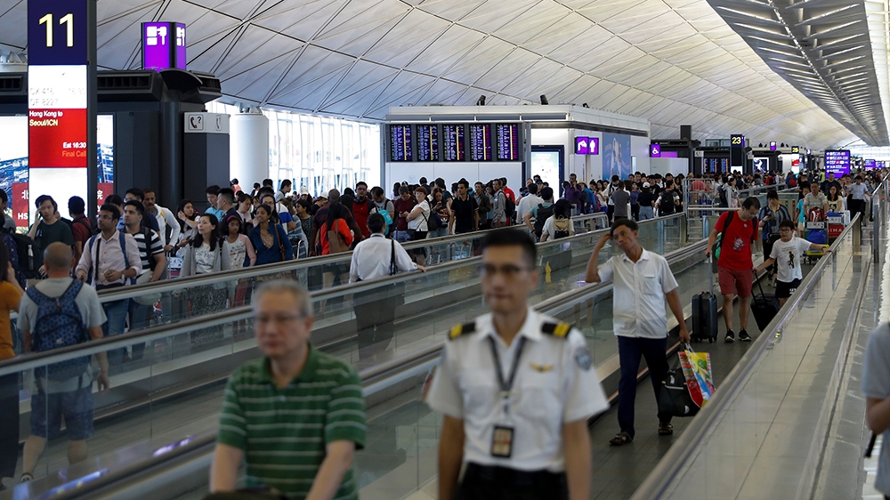 Traveller walk at the departure hall as flights information boards displaying numerous flights was cancel ay the Hong Kong International airport, Monday, Aug. 12, 2019. One of the world’s busiest airp