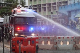 An anti-riot police vehicle equipped with a water cannon clears the road from a barricade set up by protesters during an anti-government rally in Kwai Fung and Tsuen Wan, Hong Kong, China, 25 August 2
