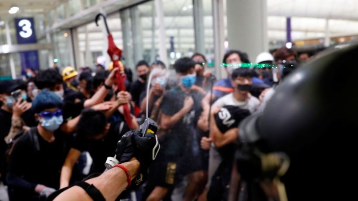 Riot police use pepper spray to disperse anti-extradition bill protesters during a mass demonstration after a woman was shot in the eye, at the Hong Kong international airport, in Hong Kong