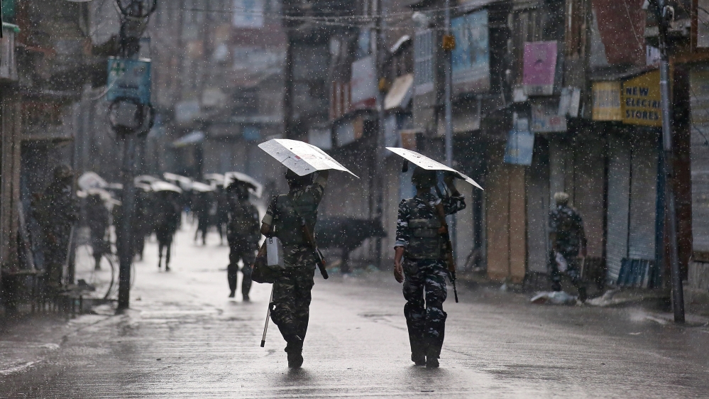 Indian security forces personnel patrol a deserted street during restrictions after the government scrapped special status for Kashmir, as it rains in Srinagar