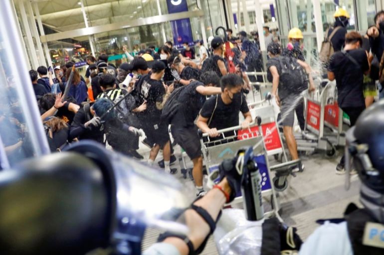 Riot police use pepper spray to disperse anti-extradition bill protesters during a mass demonstration after a woman was shot in the eye, at the Hong Kong international airport, in Hong Kong