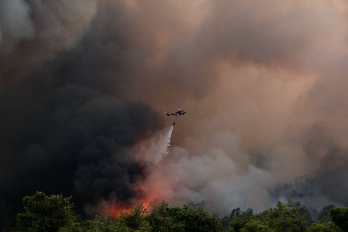 A firefighting helicopter drops water over a forest fire in Makrimalli village, on the island of Evia, northeast of Athens, Tuesday, Aug. 13, 2019. Hundreds of firefighters battled wildfires in Greece