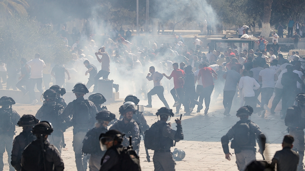 Palestinians run for cover from sound grenades at the al-Aqsa Mosque compound in the Old City of Jerusalem on August 11, 2019, as clashes broke out during the overlapping Jewish and Muslim holidays of