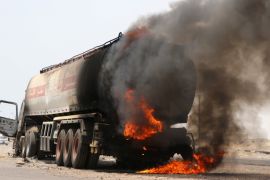 A man stands next to an oil tanker truck set ablaze during recent clashes between Yemeni southern separatists and government forces near Aden