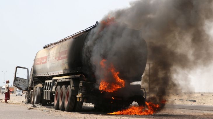 A man stands next to an oil tanker truck set ablaze during recent clashes between Yemeni southern separatists and government forces near Aden