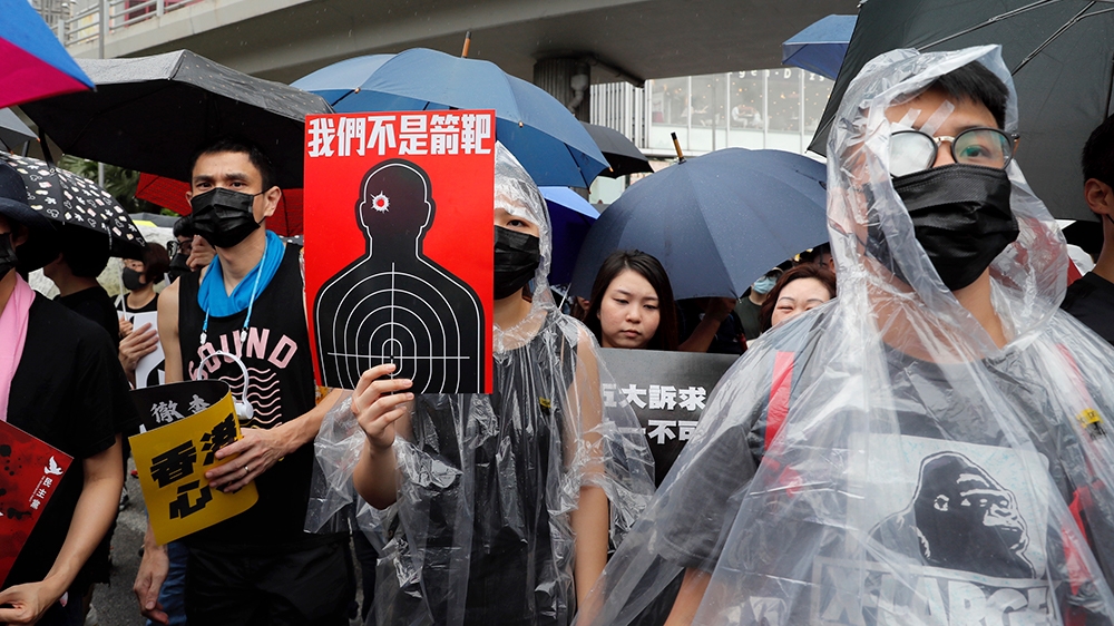 Protesters, some wearing eye patches to show solidarity to a woman reportedly injured in the eye by a beanbag fired by police, hold up a banner which reads 