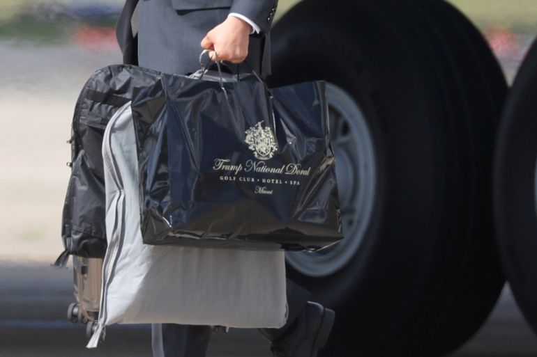 An aide carries a bag from Trump International Doral as U.S. President Trump arrives aboard Air Force One at Joint Base Andrews, Maryland