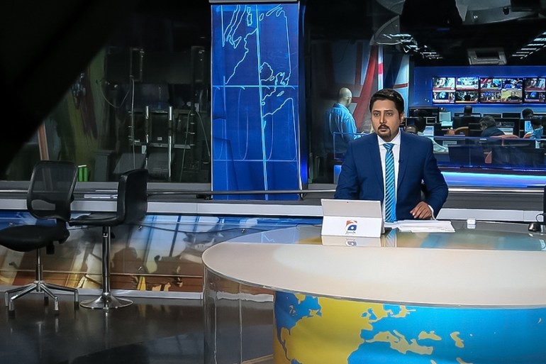 A television news anchor delivers the news at Geo News television, whose distribution was disrupted across the country, allegedly for critical coverage of the government. [Asad Hashim/Al Jazeera]