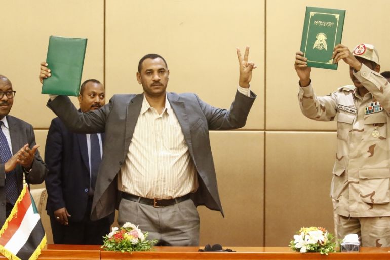 L to R) Ethiopian mediator Mahmoud Drir, protest leader Ahmad Rabie, and General Mohamed Hamdan Daglo, Sudan''s deputy head of the Transitional Military Council, celebrate after signing the constitutio