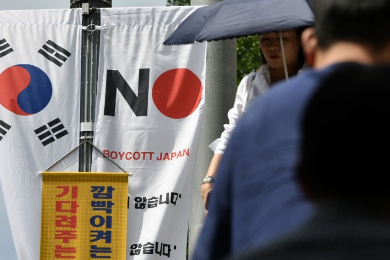 Pedestrians walk past a South Korean flag (L) and a banner (R) that reads "Boycott Japan" hanging along a street in Seoul''s Jung-gu district on August 6, 2019. A Seoul district starting putting up mor