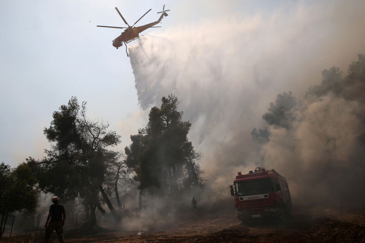 A firefighting helicopter makes a water drop as a wildfire burns in the village of Makrimalli on the island of Evia, Greece, August 14, 2019. REUTERS/Costas Baltas
