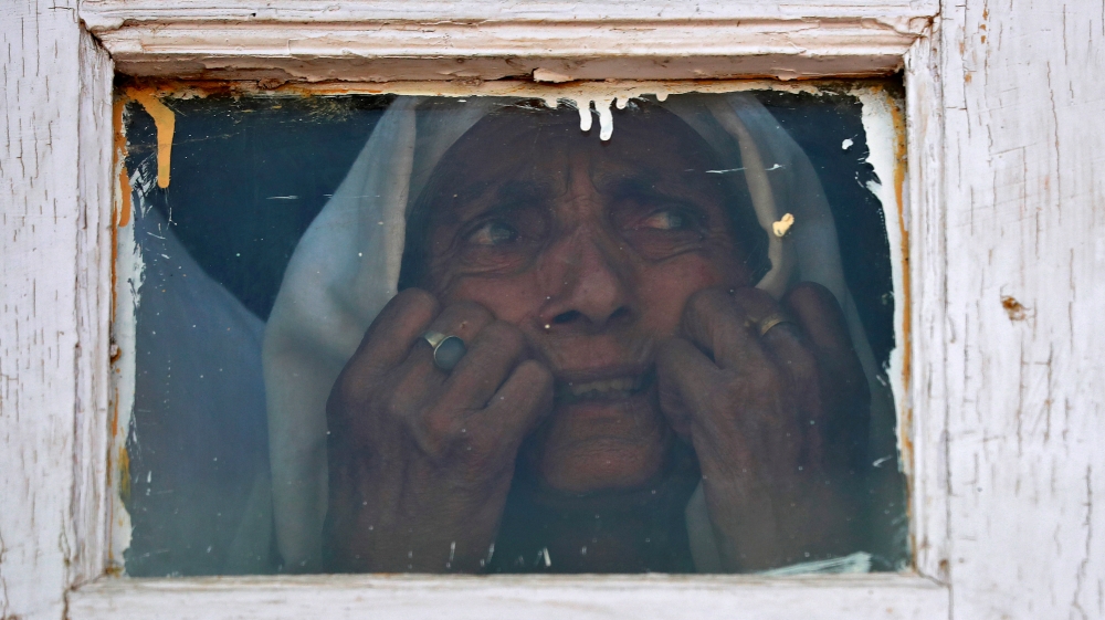 A Kashmiri woman reacts as she looks out from a window of a mosque at a protest site after Friday prayers during restrictions, in Srinagar