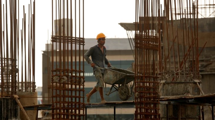 A worker pushes a wheelbarrow to collect cement at a construction site of a residential building in Mumbai