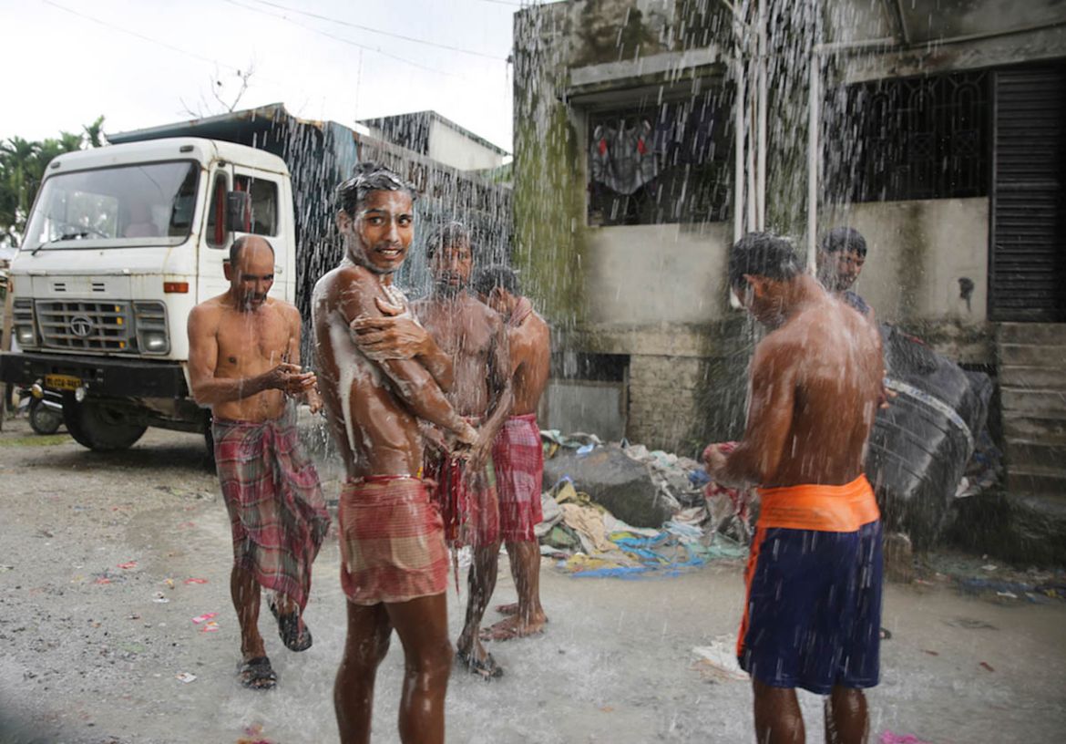 Workers take a community shower after finishing their shift at the stone breaking site in Birpara area of Dooars region.