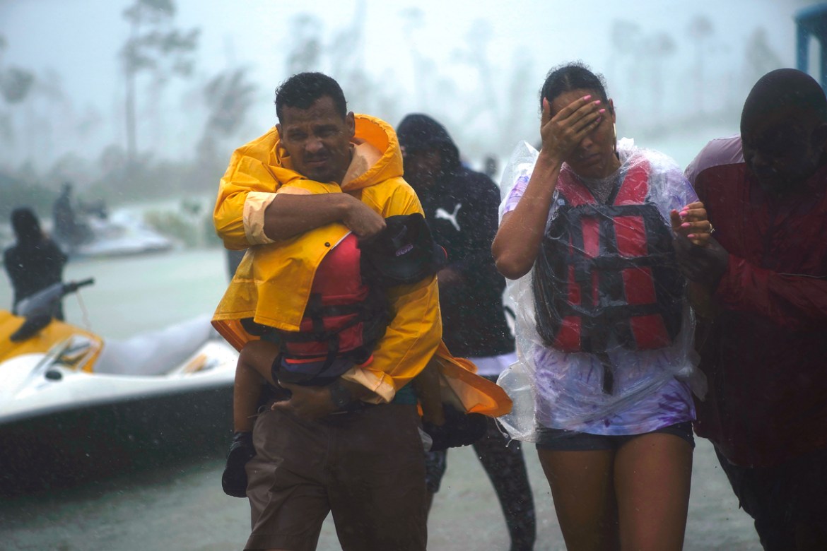 A family is escorted to a safe zone after they were rescued as Hurricane Dorian continues to rain in Freeport, Bahamas, Tuesday, Sept. 3, 2019. The center of Hurricane Dorian is finally moving away fr