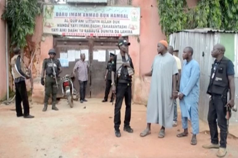Police officers stand with detained islamic teachers in the northern city of Kaduna