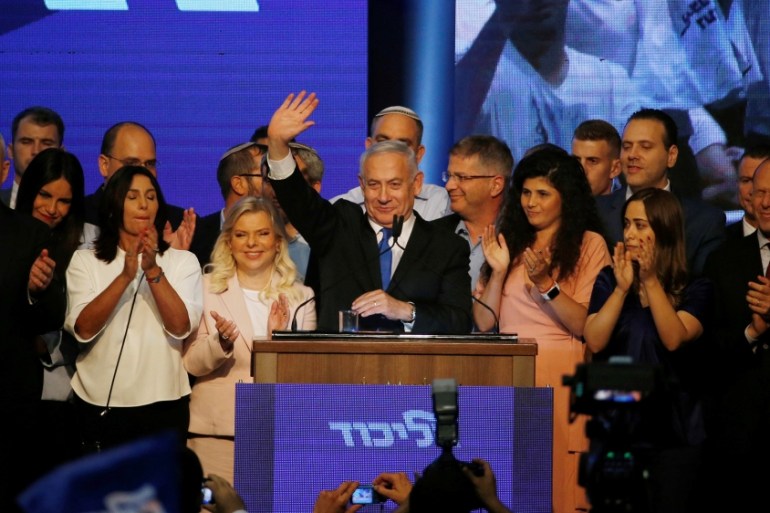 Israeli Prime Minister Benjamin Netanyahu stands next to his wife Sara as he waves to supporters at his Likud party headquarters following the announcement of exit polls during Israel''s parliamentary