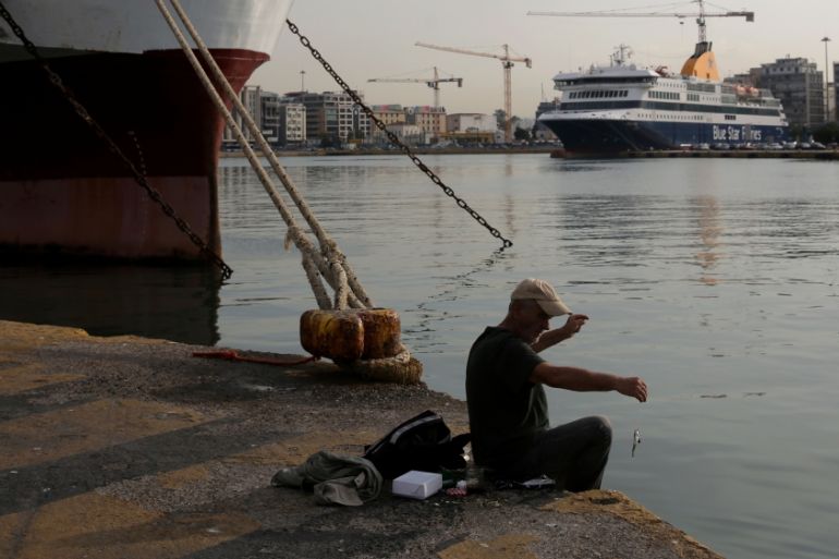 A man fishes as passenger ferries are moored during a 24-hour strike of Greece''s seamen''s federation PNO against austerity policies affecting their sector, at the port of Piraeus