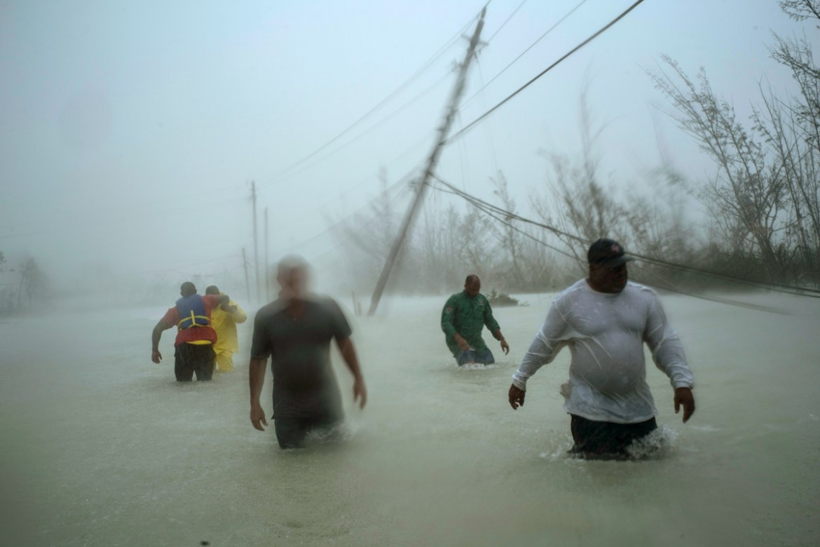Volunteers walk under the wind and rain from Hurricane Dorian through a flooded road as they work to rescue families near the Causarina bridge in Freeport, Grand Bahama, Bahamas, Tuesday, Sept. 3, 201
