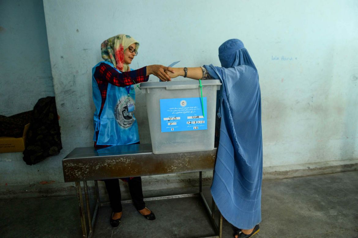 An Independent Election Commission (IEC) official (L) helps a burqa-clad woman to cast her vote at a polling station in Herat on September 28, 2019. Insurgents worked to disrupt Afghanistan''s presiden