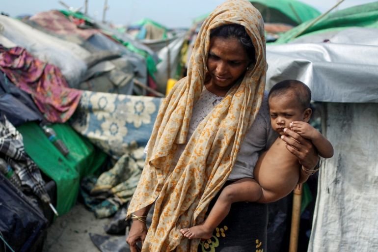 A Rohingya Muslim woman holds a baby as they wait to cross the border to go to Bangladesh, in a temporary camp outside Maungdaw, northern Rakhine state, Myanmar November 12, 2017.