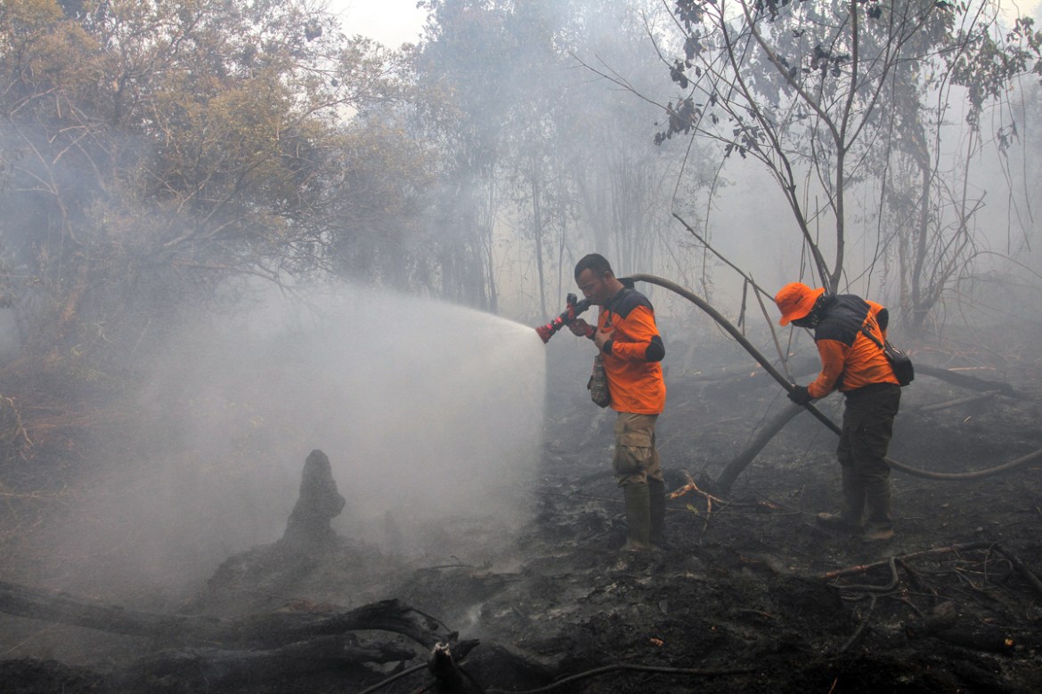 Indonesian firemen spray water to extinguish fire on a peatland in Kampar, Riau province, Indonesia, 17 September 2019. Firefighters, military personnel and water-bombing helicopters have been deploye