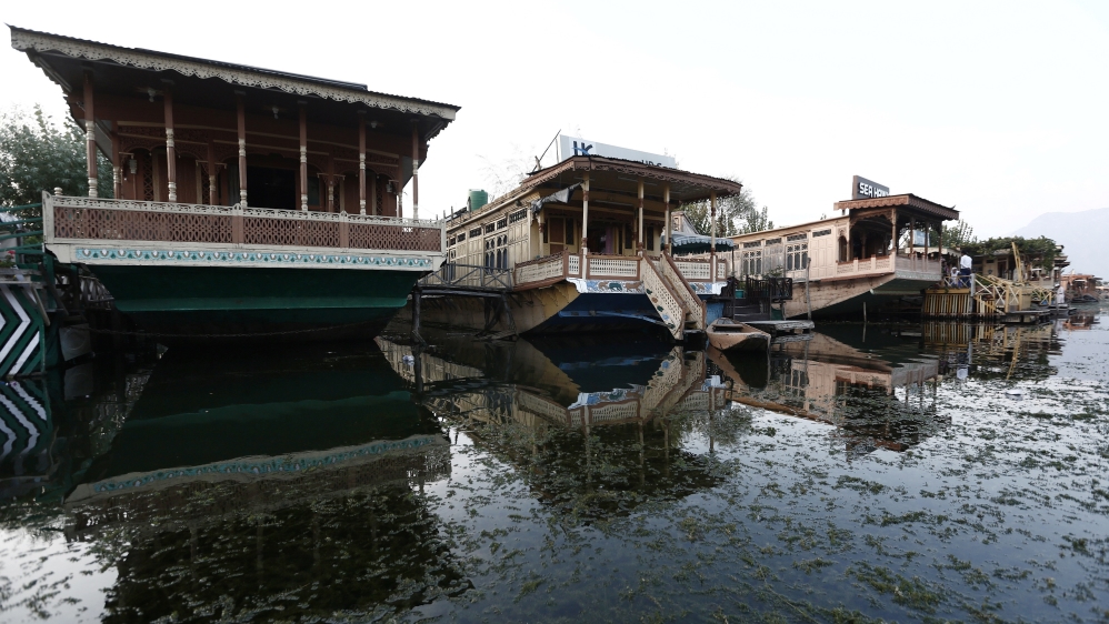 Weed is seen in the waters of Dal Lake next to empty houseboats during restrictions, after scrapping of the special constitutional status for Kashmir by the Indian government, in Srinagar