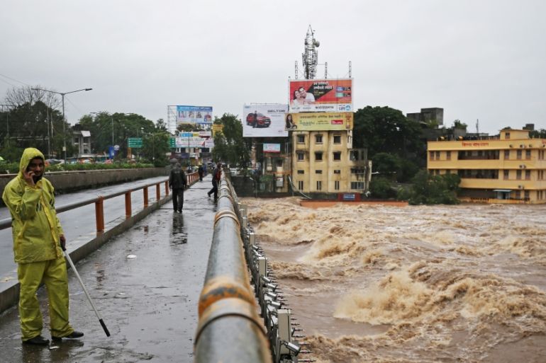 A policeman stands on a bridge as houses are seen submerged in the waters of overflowing river Godavari after heavy rainfall in Nashik