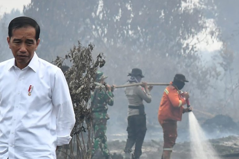 This handout picture taken on September 17, 2019 shows Indonesian President Joko Widodo inspecting the damages from the ongoing forest fires in Pekanbaru. - Indonesia has arrested nearly 200 people ov