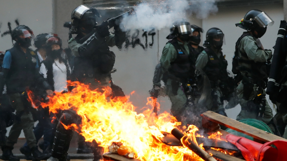 A police officer fires tear gas near a burning barricade during an anti-government protest in Hong Kong, China, October 20, 2019