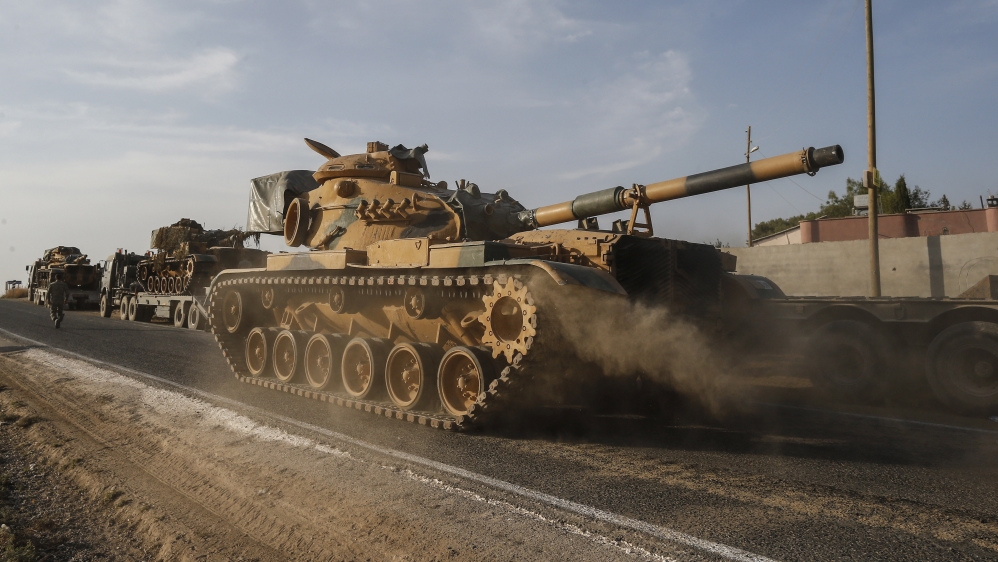 A Turkish forces tank is driven to its new position after was transported by trucks, on a road towards the border with Syria in Sanliurfa province, Turkey, on Monday, Oct. 14, 2019