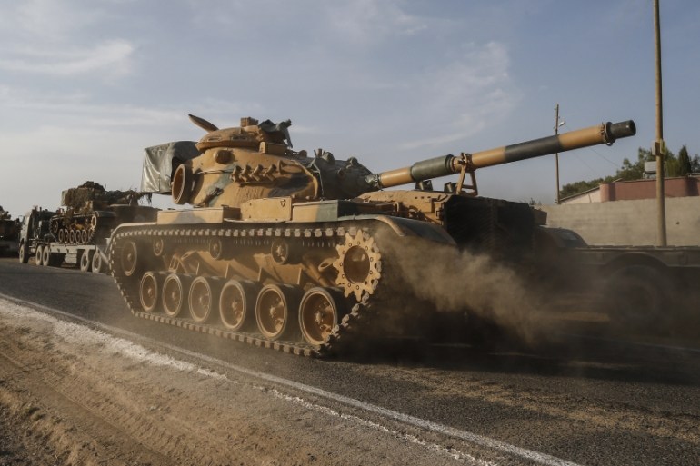A Turkish forces tank is driven to its new position after was transported by trucks, on a road towards the border with Syria in Sanliurfa province, Turkey, on Monday, Oct. 14, 2019