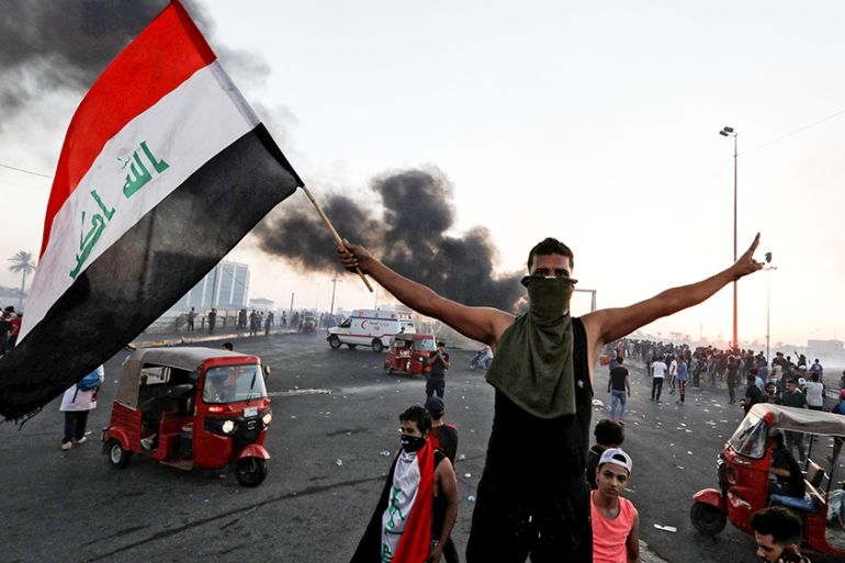 A demonstrator holds an Iraqi flag at a protest after the lifting of the curfew, following four days of nationwide anti-government protests that turned violent, in Baghdad, Iraq October 5, 2019. REUTE