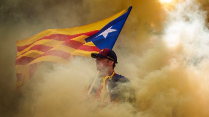A man holding an independence flag is seen through the smoke thrown by demonstrators during the Catalan National Day in Barcelona, Spain, Wednesday, Sept. 11, 2019.
